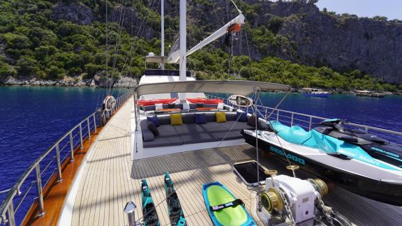 Luxuriöses Vordeck der Queen of Makri mit komfortabler Lounge und vielfältiger Wassersportausrüstung.