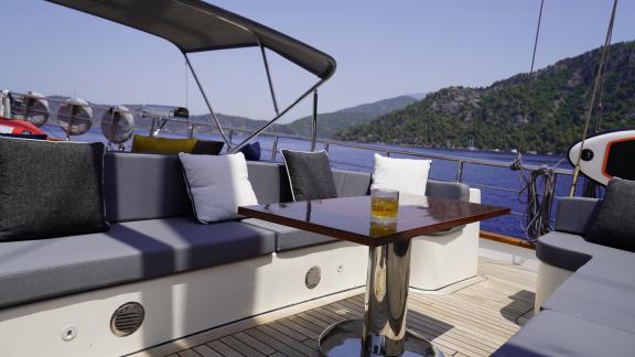 Komfortable Sitzecke mit Tisch auf dem Deck der Queen of Makri, perfekt für entspannte Stunden mit Meerblick.