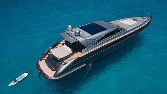 Die Yacht Zazzazu liegt im türkisfarbenen Wasser. Am Heck befinden sich Loungefläche und Paddleboard.