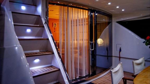 On Noi Quattro in Trogir, the aft deck, lit stairs, glass door and teak floor are visible for private yacht charter.