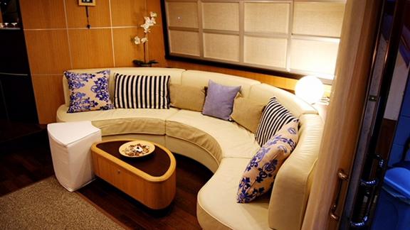 On Noi Quattro in Trogir, curved sofa, patterned cushions, table and warm saloon light are seen for yacht charter.