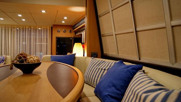 On Noi Quattro in Trogir, table, blue cushions, curtains and warm saloon light are seen for private yacht hire.