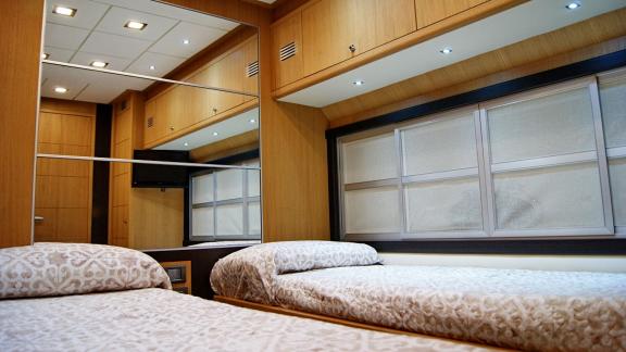 On Noi Quattro in Trogir, twin beds, mirrored wall, window and warm cabin light are seen for yacht charter.