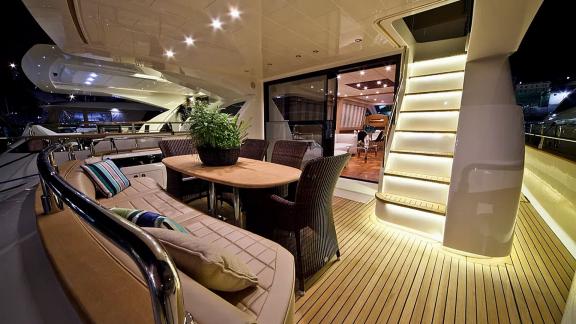 On Sea Side in Trogir, the night aft deck, dining table, seating, lit stairs and saloon entrance are seen for charter.