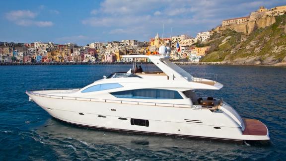 In Trogir, Sea Side motor yacht cruises on blue sea with coastal town behind for a weekly yacht charter.