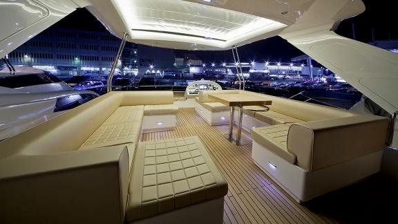 On Sea Side in Trogir, the lit flybridge, lounge seats, table and helm are seen for weekly yacht charter.