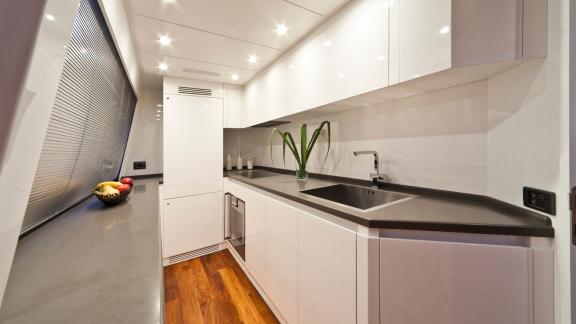 On Sea Side in Trogir, the white galley, sink, counter, window and wood floor are visible for weekly yacht hire.