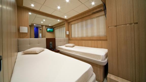 On Sea Side in Trogir, the twin cabin shows two single beds, wood closet, window and ceiling lights for weekly yacht hir