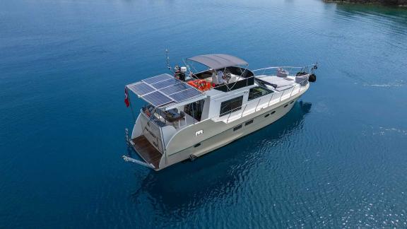 Motor yacht Ada Kuzey preparing to anchor in a tranquil bay, showcasing its striking top view.