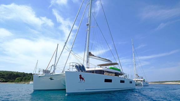 Lagoon 620 Adriatic Lion peacefully anchored in crystal-clear water near the Croatian coast, available for rent with ski