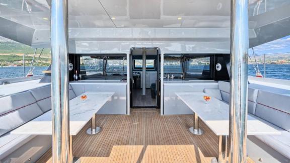 Split açıklarında demirli Luna 49 Red katamaranın arka güvertesi gölgelikli, masa ve minderli koltuklarla donatılmış.