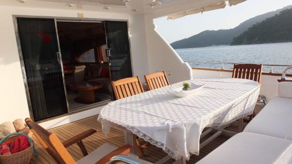 Esstisch auf dem Achterdeck der Motoryacht Ser 1 mit Meerblick und bequemen Stühlen.