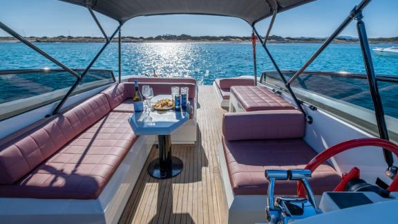 The open cockpit of the Tequila motor yacht features elegant seating and a table, perfect for enjoying the sea view.