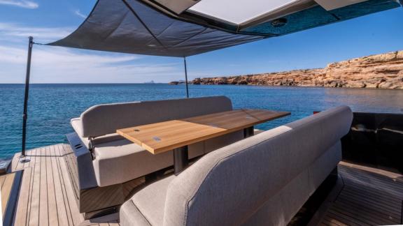 The shaded seating area on the aft deck of Jemima motor yacht offers a peaceful view of the sea.