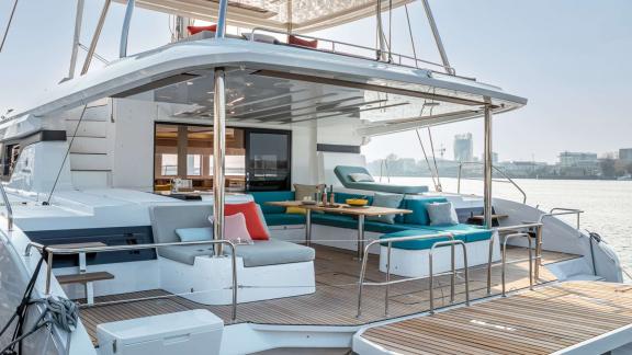 The aft deck of catamaran Happy features cozy seating and tables, perfect for relaxing outdoors.