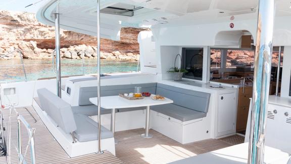 The aft deck of the Balok catamaran features a cozy dining area and an open kitchen.