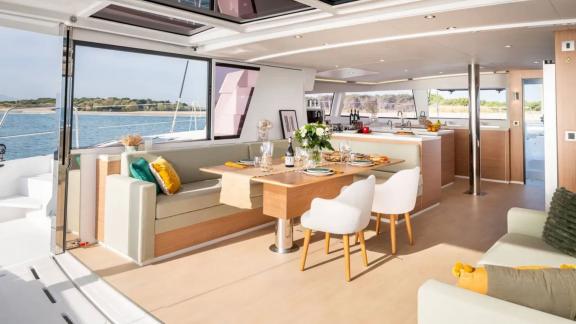 Spacious dining area on the Sahana catamaran, furnished with modern furniture and a sea view.