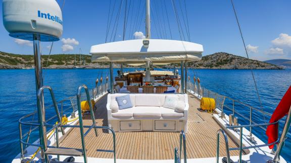 The aft deck of Gazella features a large white sofa with a sea view and a dining area.