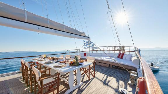 The deck of White Pearl gulet in Athens features a dining table and spacious seating area.
