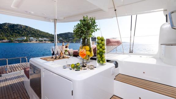 The bar area of Dream catamaran features fruit carafes, cocktail glasses, and a stylish sea view.