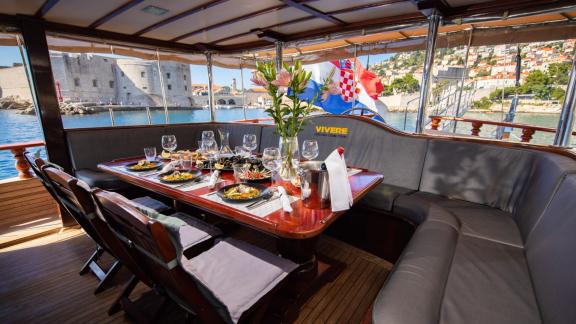 Set outdoor dining table on the gulet Vivere with a view of the historic old town of Dubrovnik, Croatia.