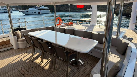 The aft deck of Angelo 3 features a large table and a comfortable seating area.