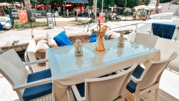 The aft deck of the motor yacht Hayalim features a seating area with a table and chairs.