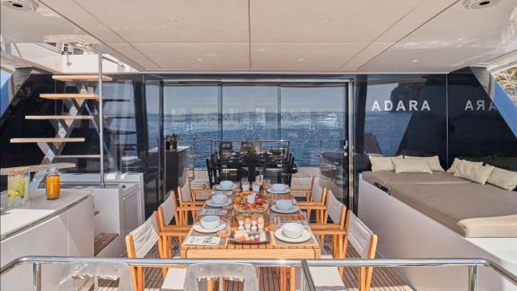 The aft deck of Adara yacht offers a spacious table, elegant settings, and a cozy spot for dining.