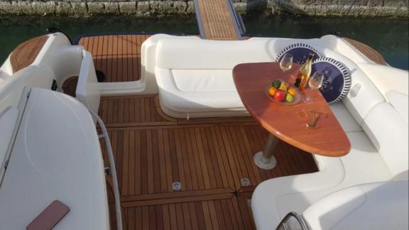 Das Heckdeck der Yacht Blondie bietet eine gemütliche Sitzecke mit einem Holztisch, gedeckt mit Obst und Getränken.