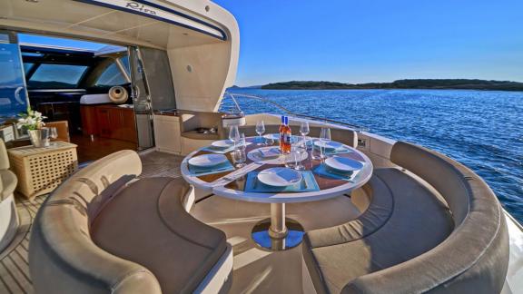 Auf dem Achterdeck der Sea U Motoryacht vor Athen ist ein runder Tisch gedeckt.
