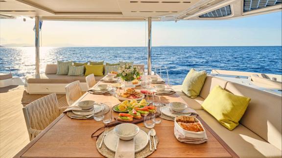 Aft deck table set with fruits and snacks facing the open sea view.