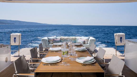 In Kastela the aft deck of Vulpino shows a set table and sofa facing the open sea.