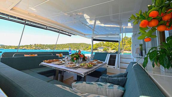 The aft deck of Ace of Hearts in Athens features a prepared dining table and seating area.