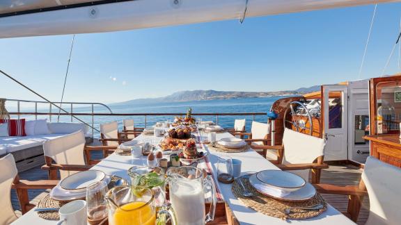 On the deck of White Pearl gulet in Athens, a rich breakfast table is set with a sea view.