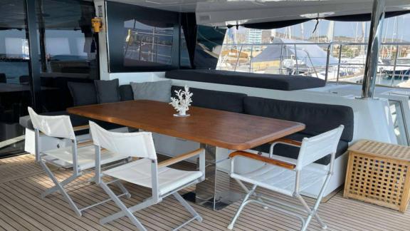 Stylish covered dining area with a wooden table and comfortable seating on the Lagoon 630 Pearly Gates in Lavrion harbor