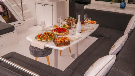 Close-up of an elegant breakfast table with fresh fruit and pastries in the outdoor area of the Daphne catamaran.