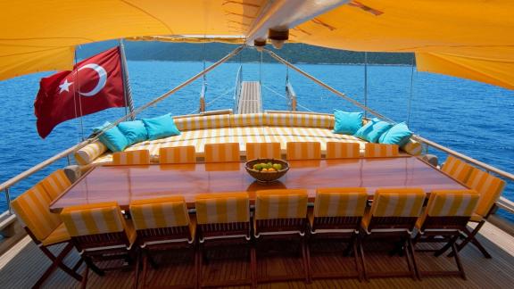 The stylish dining area on the deck of the Flas VII, with a view of the sea and a Turkish flag in the background.