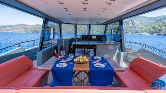 Essbereich auf dem Deck der motoryacht Gottiri mit stilvollem Tisch und Blick auf die Landschaft.