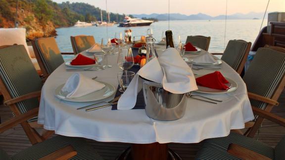 Stilvoll gedeckter Tisch auf dem Deck der Grande Mare, mit Blick auf das ruhige Meer und umgebende Yachten. Ideal für ex