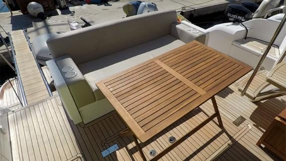 The wooden table and seating area on the aft deck of the Get Lucky motor yacht offer a comfortable dining experience.