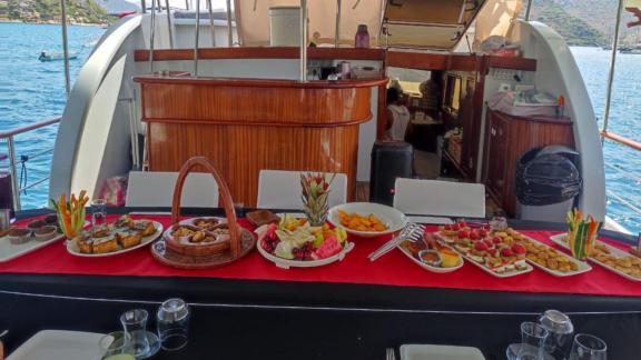 Set dining table with various appetizers and fruits on the deck of a yacht.