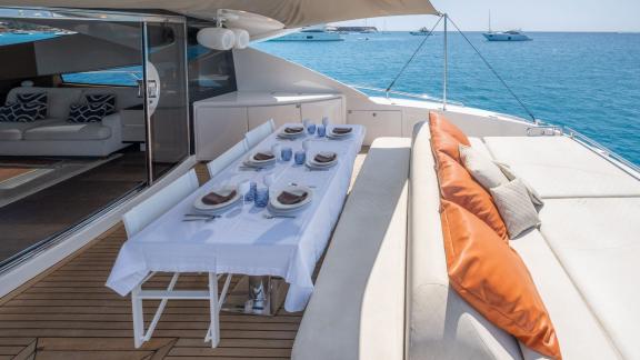 The aft deck of motor yacht Funky Town features a dining area and a comfortable relaxation space.