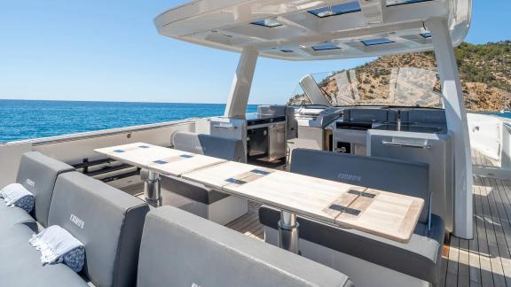 Sitzgruppe mit grauen Kissen und langem Esstisch auf dem Deck der Motoryacht Petitchet.
