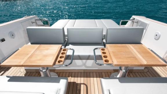 The aft section of the Bombon motor yacht features two wooden tables and leather seating.