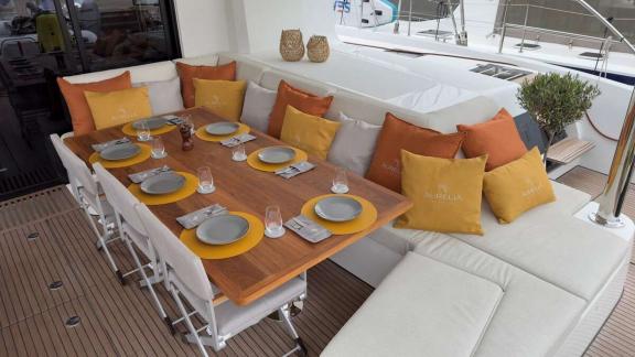 On Aurelia’s deck, a cozy dining space is set with elegant plates and soft cushions.