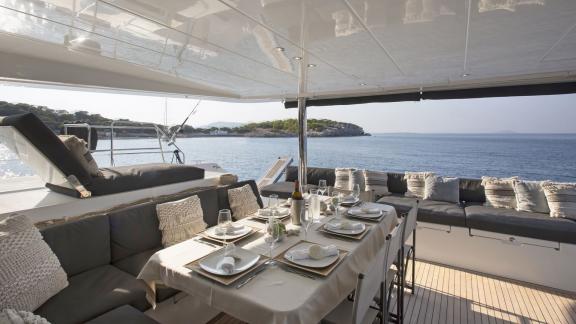 The dining area of the Lagoon 560 in Athens, elegantly set and surrounded by comfortable seating with a view of the sea.