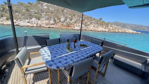 Aft deck of Fundamental B with comfortable seating and table, offering a sea view.