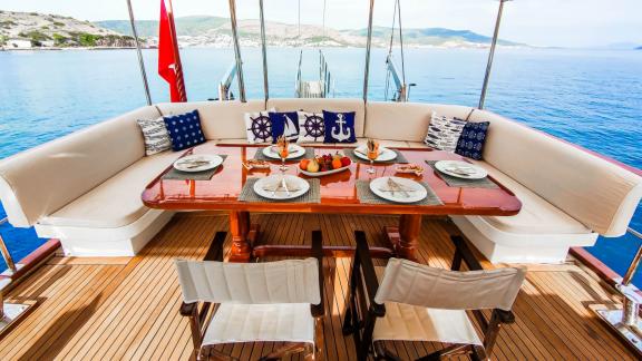 A stylishly set dining table on Gulet Cagan 2, with maritime decor and views of the calm sea, perfect for a relaxing mea