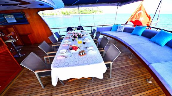 Stylishly laid dining table on the Gulet Maya, with a view of the sea and the coast of Fethiye.