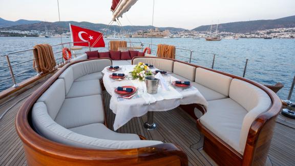 Ein gedeckter Esstisch auf dem Deck einer Segelyacht mit türkischer Flagge.